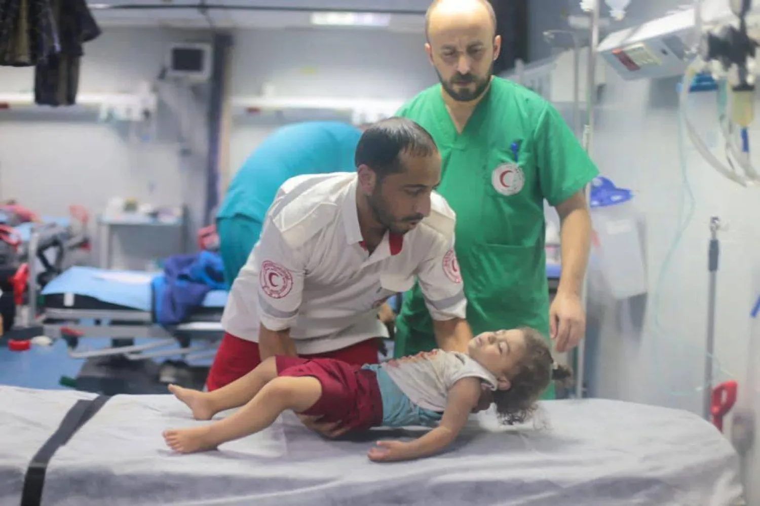 
مسعف من الهلال الأحمر الفلسطيني يستقبل طفلة في مستشفى القدس بعد قصف إسرائيلي على غزة (الصفحة الرسمية للهلال الأحمر الفلسطيني بفيسبوك)
