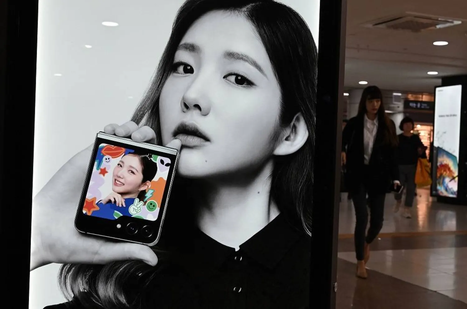 A woman walks past an advertisement for Samsung Galaxy Z Flip5 phone at an underground shopping area in Seoul in Seoul on October 11, 2023. (AFP)