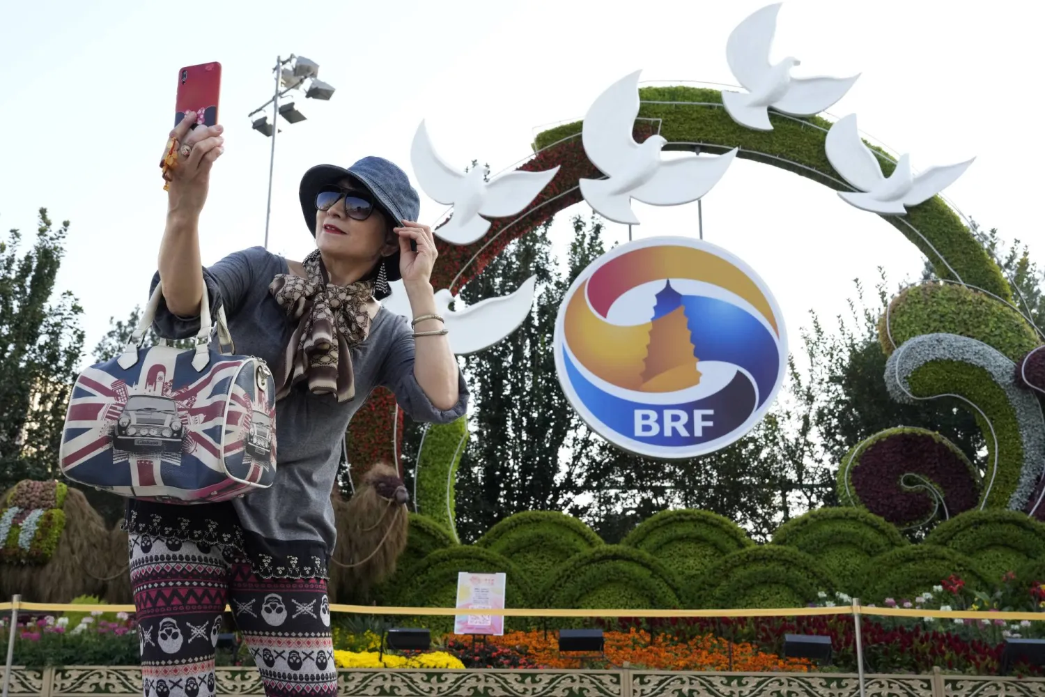 صينية تلتقط صورة «سيلفي» أمام شعار منتدى «الحزام والطريق» في بكين الاثنين (أ.ب)