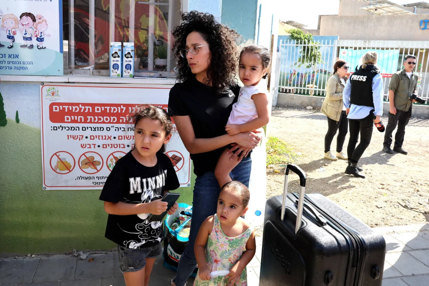 عائلة إسرائيلية تنتظر إجلاءها بحافلة من مدينة سديروت في جنوب إسرائيل  وسط المعارك المستمرة في غزة (أ.ف.ب)