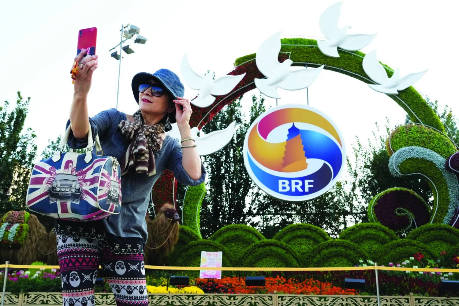 صينية تلتقط صورة «سيلفي» أمام شعار منتدى «الحزام والطريق» في بكين الاثنين (أ.ب)