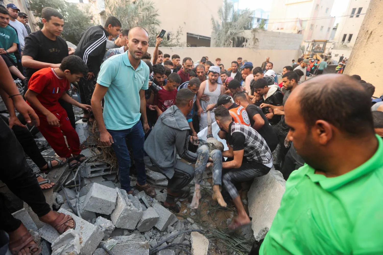 فلسطينيون ينتشلون مصابا من تحت أنقاض منزل دمرته غارات إسرائيلية في خان يونس بجنوب قطاع غزة (رويترز)