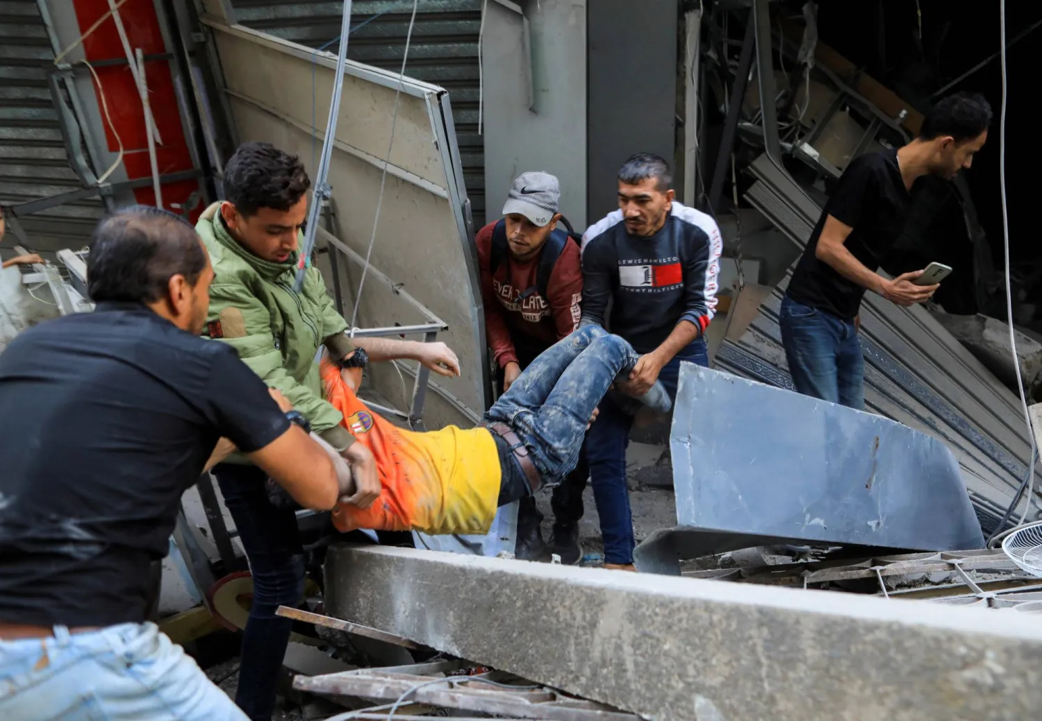 أشخاص يحملون جريحاً في موقع غارة إسرائيلية في خان يونس بجنوب قطاع غزة اليوم (رويترز)