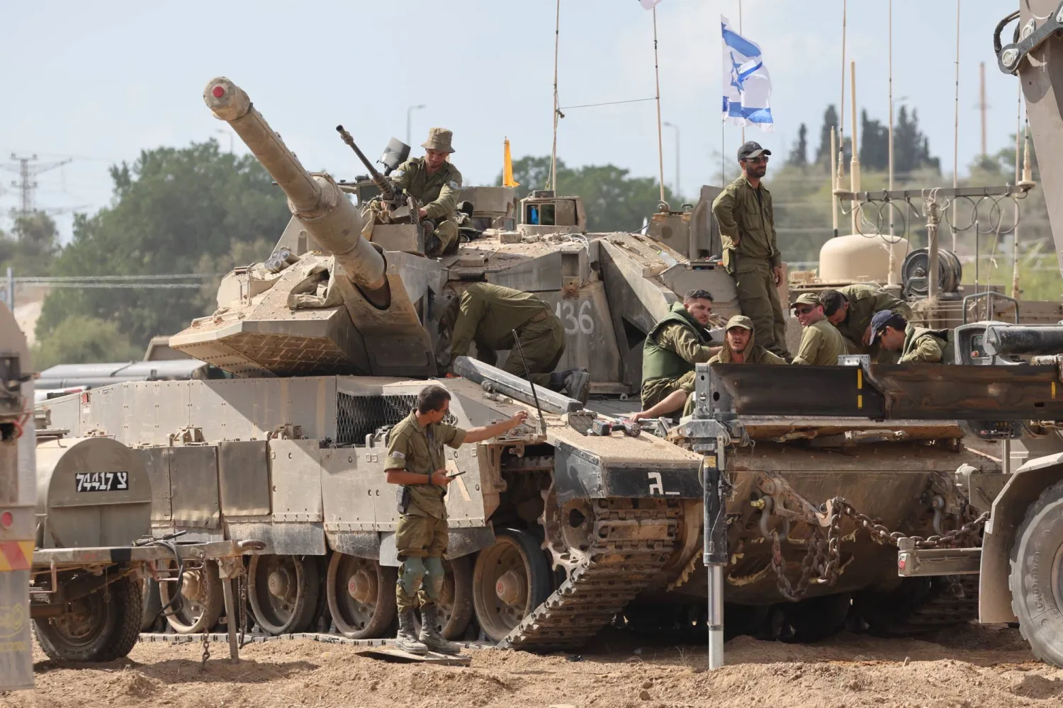 دبابة إسرائيلية حولها عدة جنود ضمن حشود إسرائيلية على حدود قطاع غزة (إ.ب.أ)