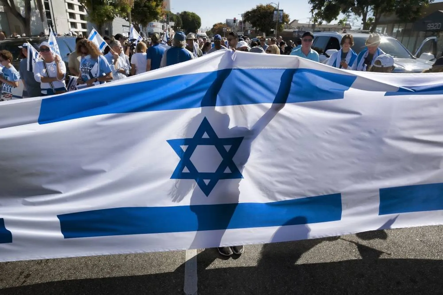 A demonstrator carries a banner decorated with the Israeli flag prior to a march in support for Israel in West Los Angeles to the Museum of Tolerance, Sunday, Oct. 15, 2023. (AP)