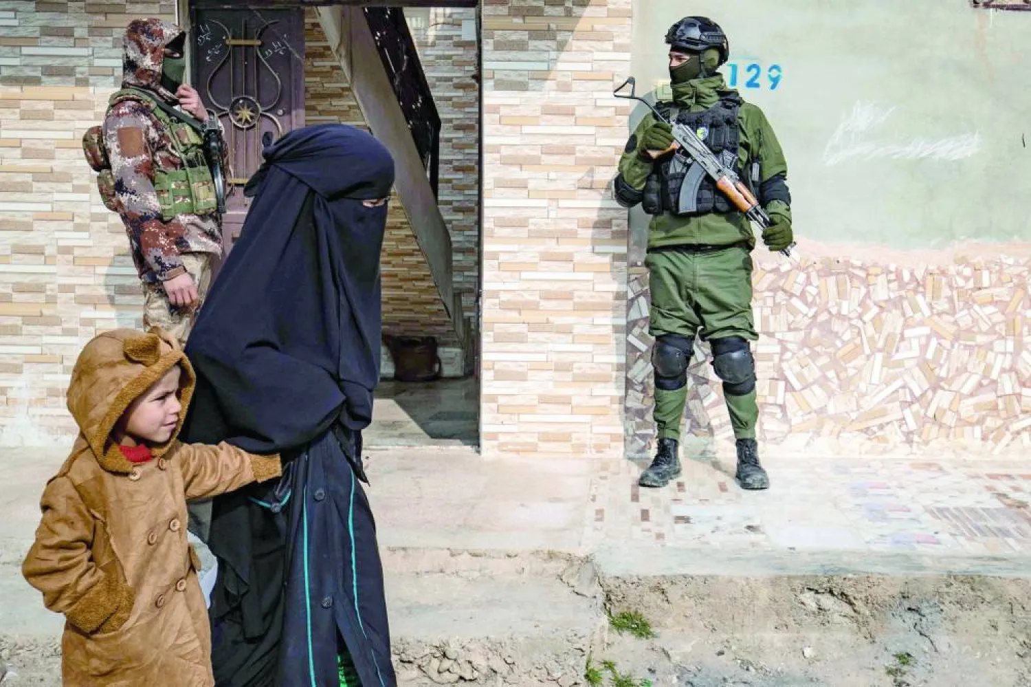 مقاتلان من «الأسايش» خارج منزل خلال عملية مداهمة في الرقة في يناير 2019 (أ.ف.ب)