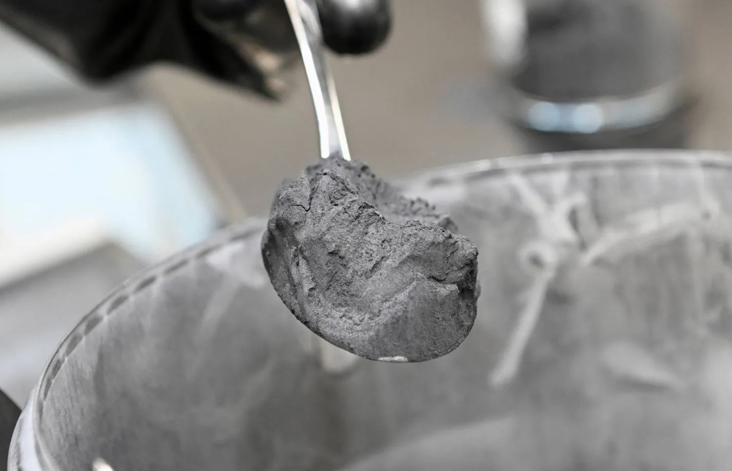 عامل يحمل ملعقة مليئة بالغرافيت في أحد مصانع إنتاج بطاريات السيارات التابعة لشركة «فولكسفاغن» الألمانية (رويترز)