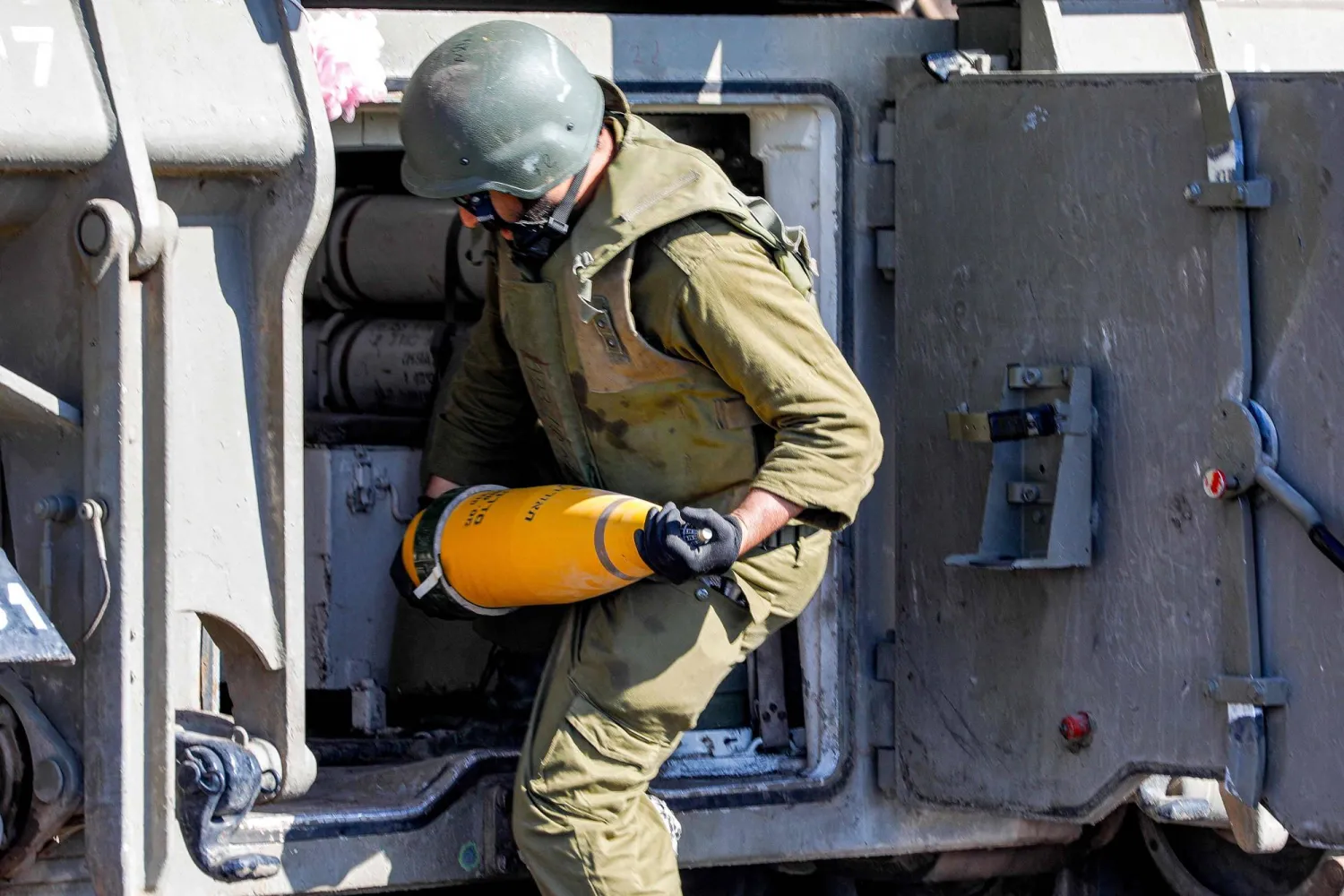 جندي إسرائيلي يضع قذيفة عيار 155 مم داخل مدفع هاوتزر على الحدود مع لبنان (أ.ف.ب)