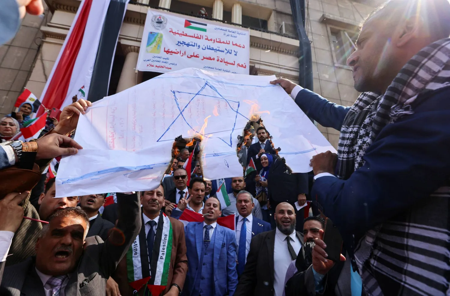 محامون مصريون يحرقون لافتات تصور العلم الإسرائيلي خلال احتجاج دعماً للفلسطينيين في 22 أكتوبر 2023 (رويترز)