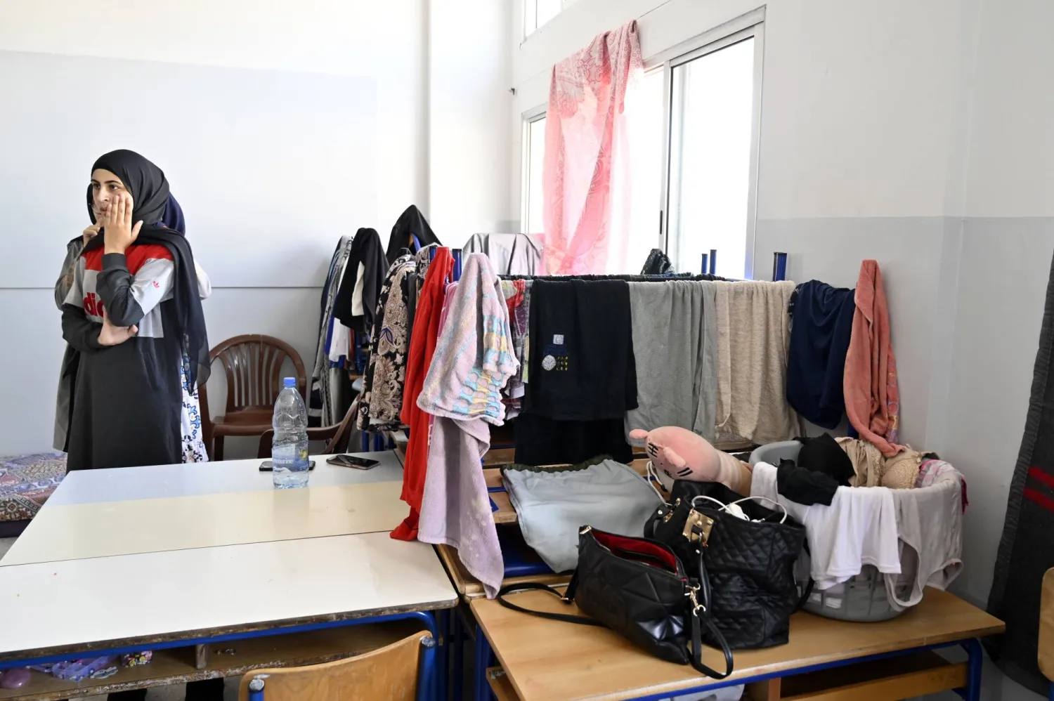 نازحات من جنوب لبنان يقفن في صف إحدى المدارس المحلية التي تُستخدم مأوىً بمدينة صور الساحلية جنوب لبنان يوم 23 أكتوبر 2023 (إ.ب.أ)