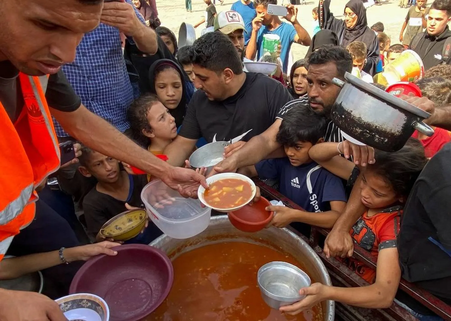 Palestinians, who fled their houses due to Israeli strikes, gather to get their share of charity food offered by volunteers, amid food shortages, at a UN-run school where they take refuge, in Rafah, in the southern Gaza Strip, October 23, 2023. (Reuters)