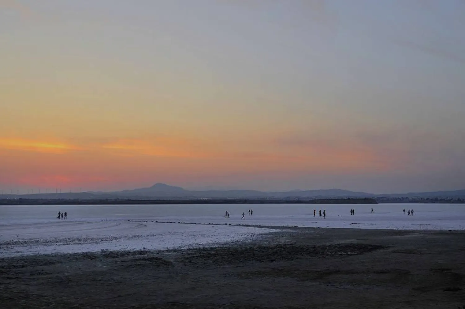 People walk at the salt lake during sunset in southern coastal city of Larnaca in the eastern Mediterranean island of Cyprus, on Monday, Oct. 23, 2023. (AP)