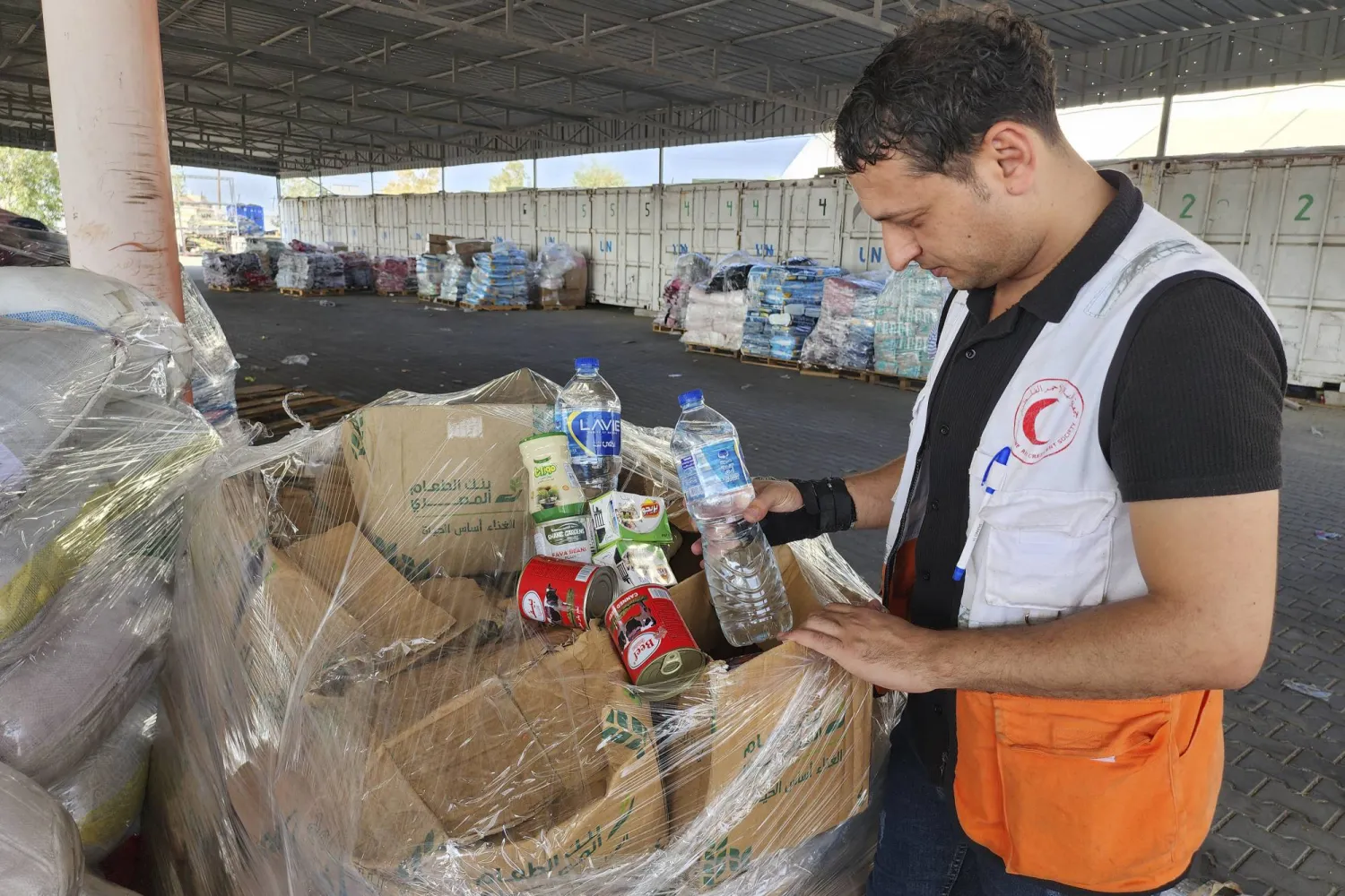 موظف في الهلال الأحمر يقوم بتحضير المساعدات الإنسانية في مركز تابع للأمم المتحدة في غزة (أ.ب)