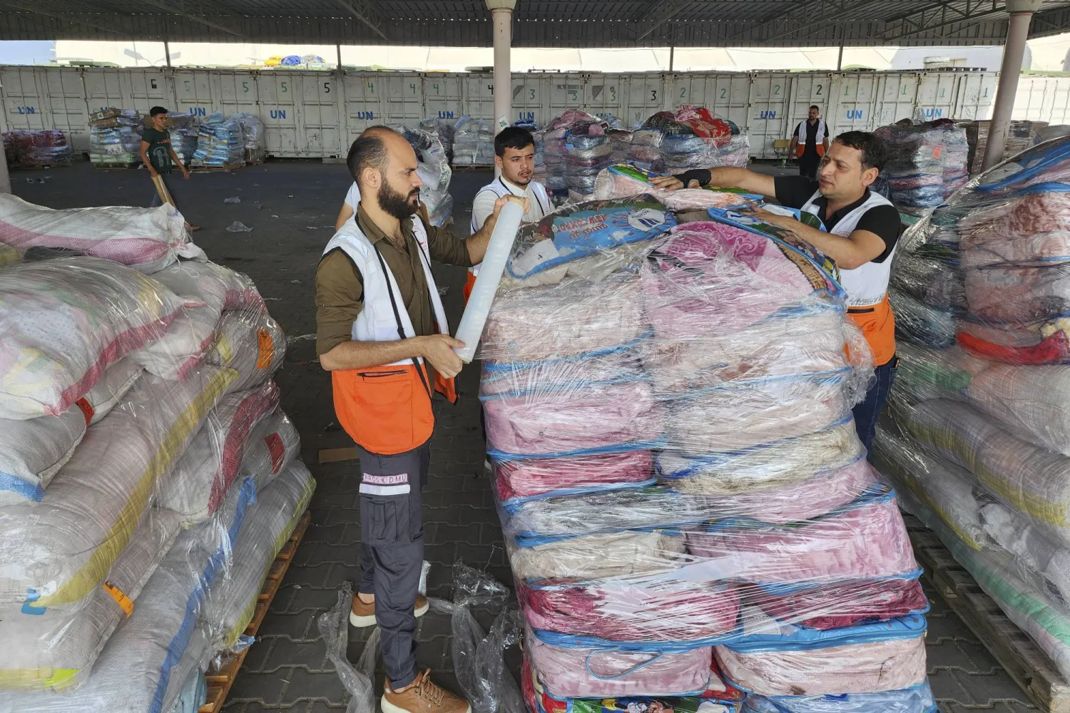 الأمم المتحدة والهلال الأحمر يقومان بإعداد المساعدات للتوزيع على الفلسطينيين في مستودع «الأونروا» بدير البلح (أ.ب)