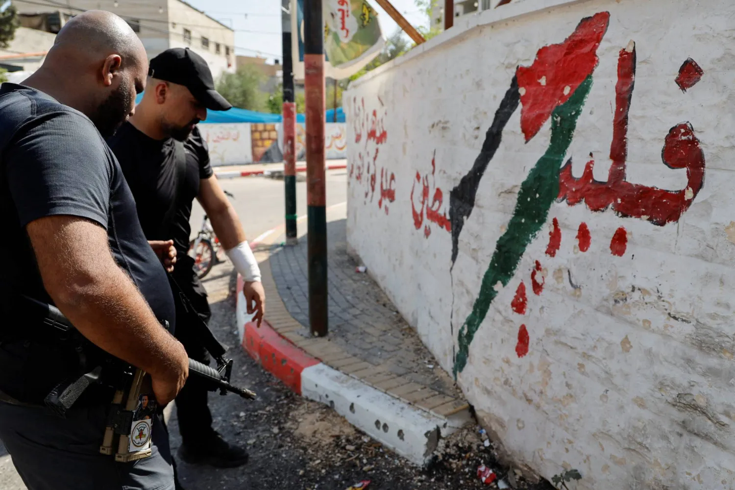 يتفقدون موقع غارة إسرائيلية بمسيّرة قتلت ثلاثة فلسطينيين في مخيم جنين بالضفة الأربعاء (رويترز)