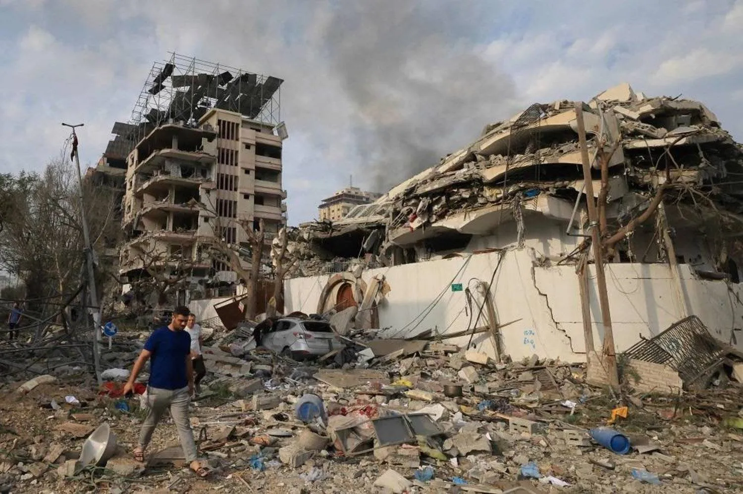 Palestinians walk through a ravaged street following Israeli airstrikes on Gaza City, on October 10, 2023. (AFP)
