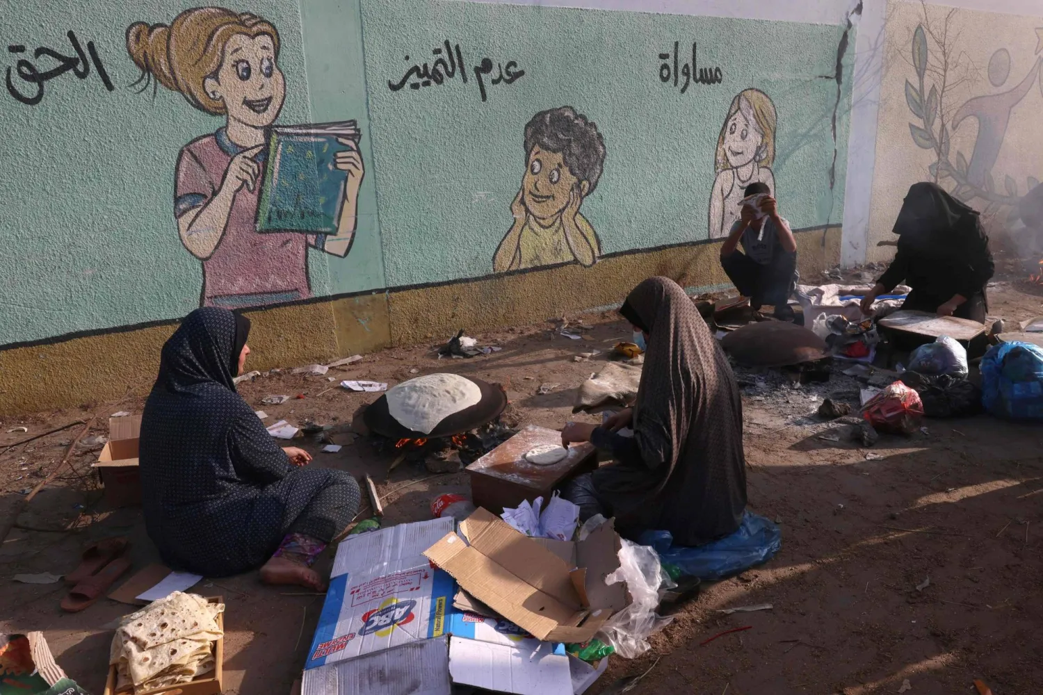 فلسطينيات يصنعن الخبز التقليدي في ملجأ للعائلات النازحة بشكل رئيسي من شمال قطاع غزة (أ.ف.ب)