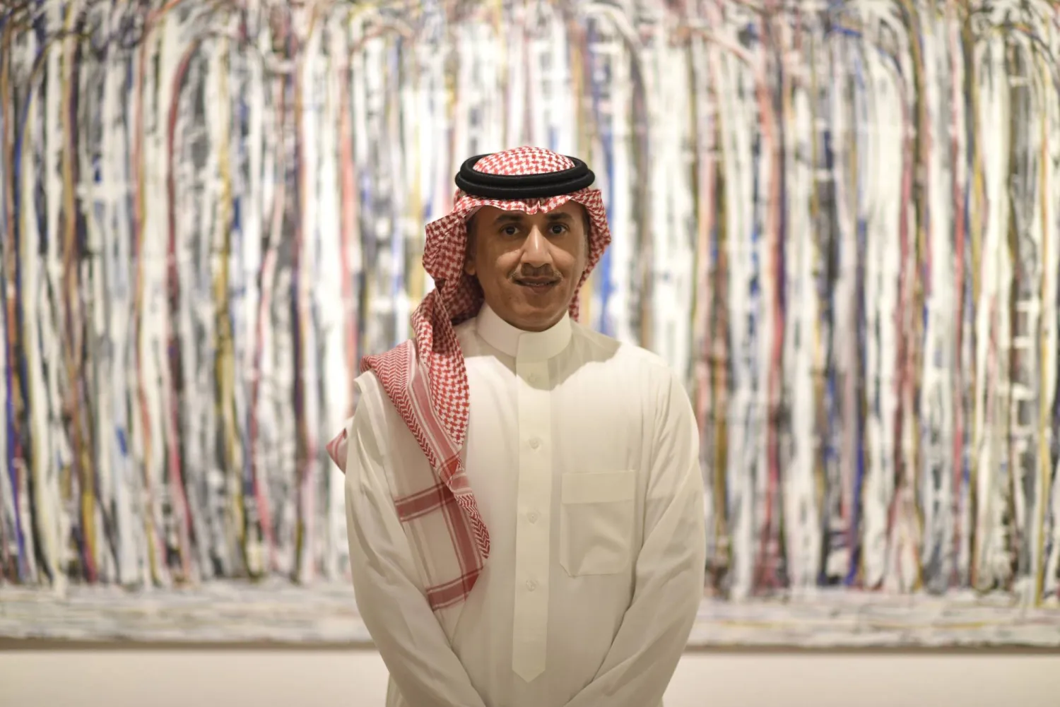 الفنان فهد النعيمة أمام إحدى لوحاته في المعرض (الشرق الأوسط)