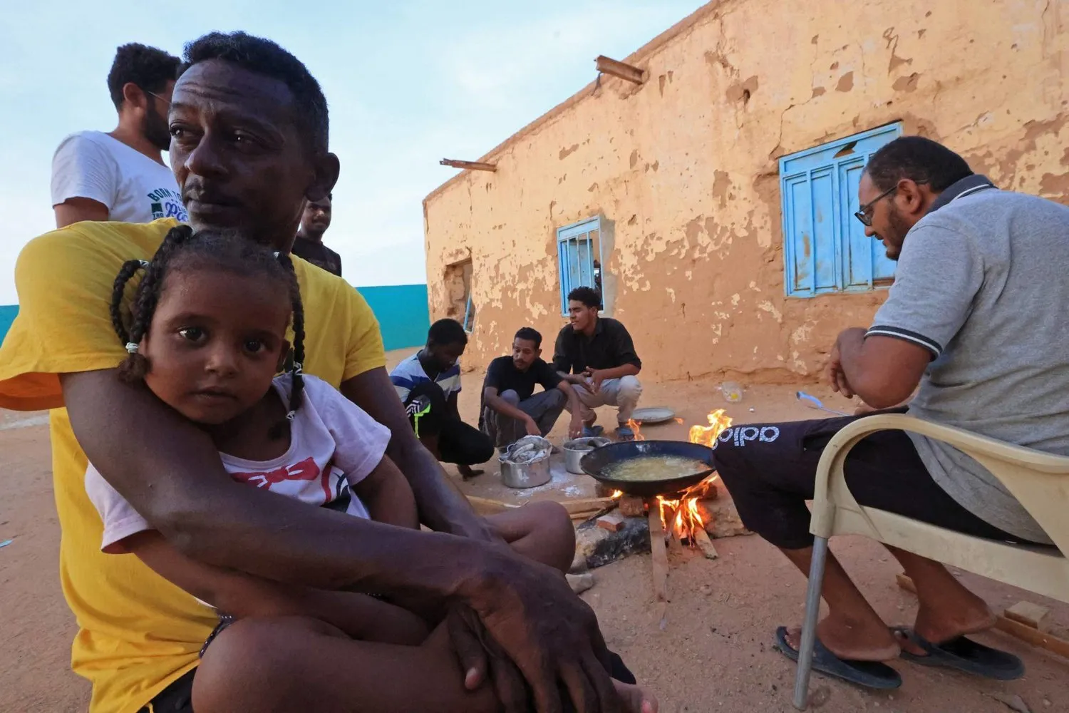 Kuzey Sudan'ın Mısır yakınlarındaki sınır kasabası Vadi Halfa'da, çatışmalar nedeniyle yerinden edilenler için sığınağa dönüştürülen okulda yemek hazırlayan gönüllüler. (AFP)