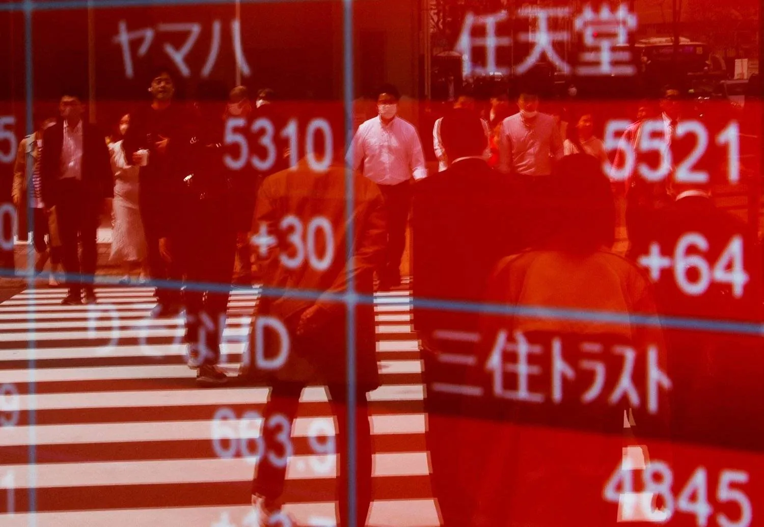 Reflection of the image of passers-by on a screen displaying stock movements on the Japanese Stock Exchange in central Tokyo. (Reuters) 