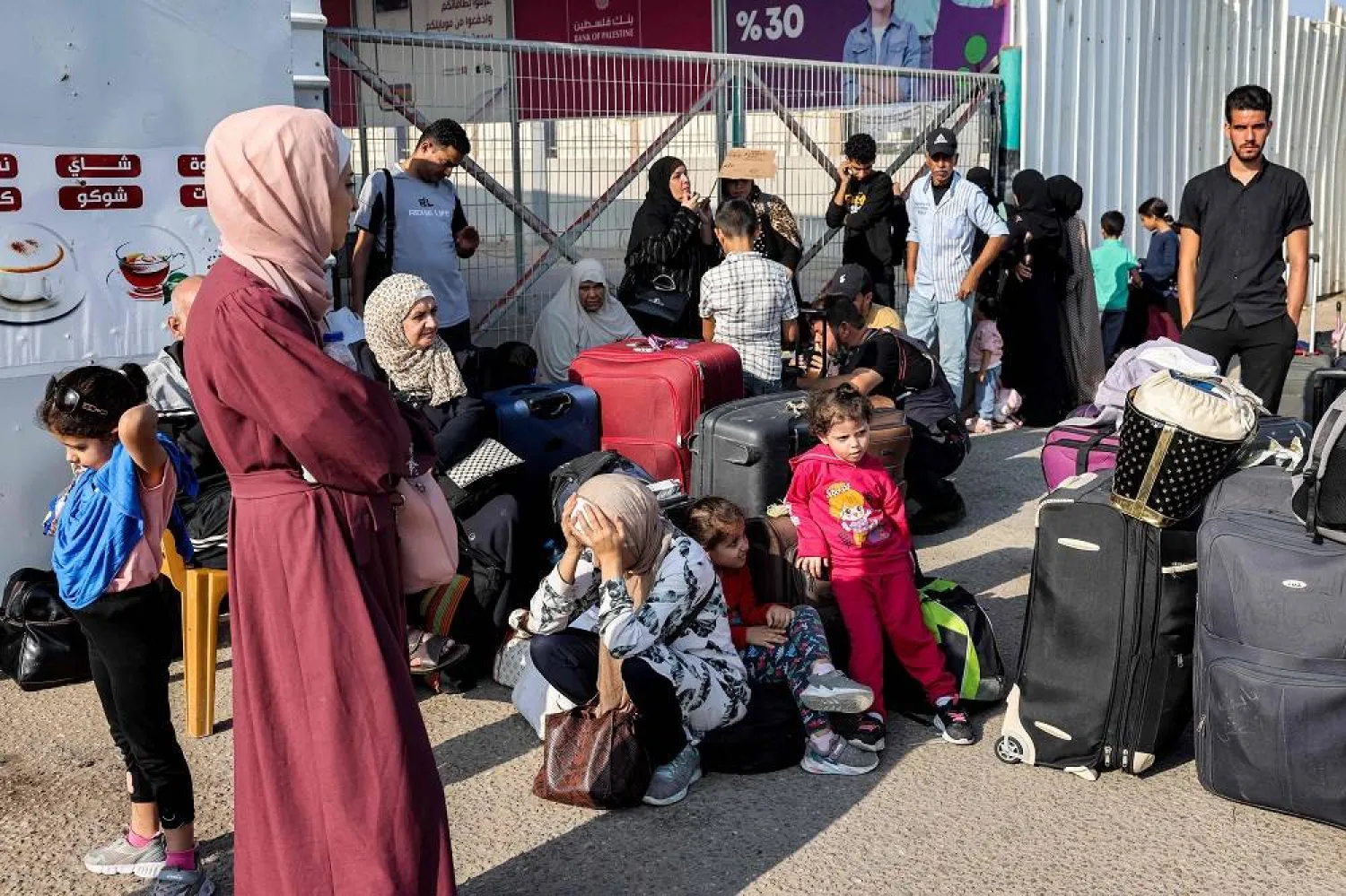 People wait at the Rafah border crossing with Egypt in the southern Gaza Strip on November 1, 2023. (AFP)