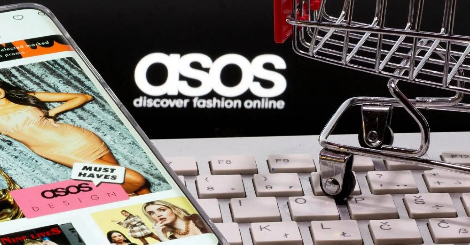 A smartphone with ASOS app, a keyboard and a shopping cart are seen in front of a displayed ASOS logo in this illustration picture taken October 13, 2020. (Reuters)