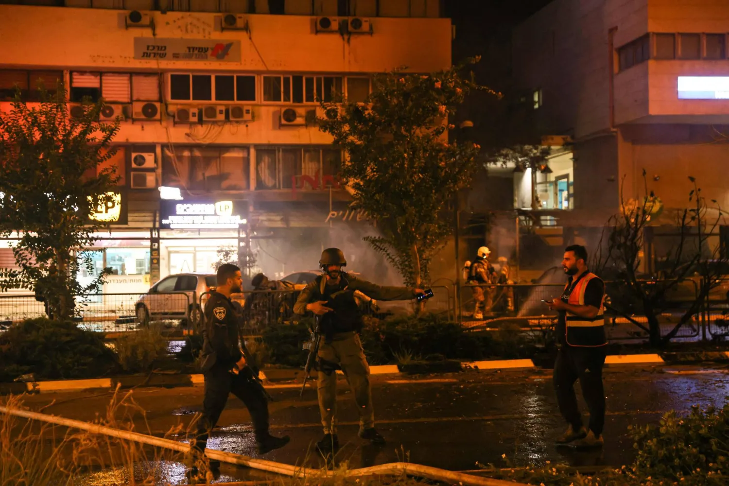 جنود إسرائيليون يحيطون بالموقع الذي سقطت فيه القذائف التي أُطلقت من جنوب لبنان على كريات شمونة (أ.ف.ب)