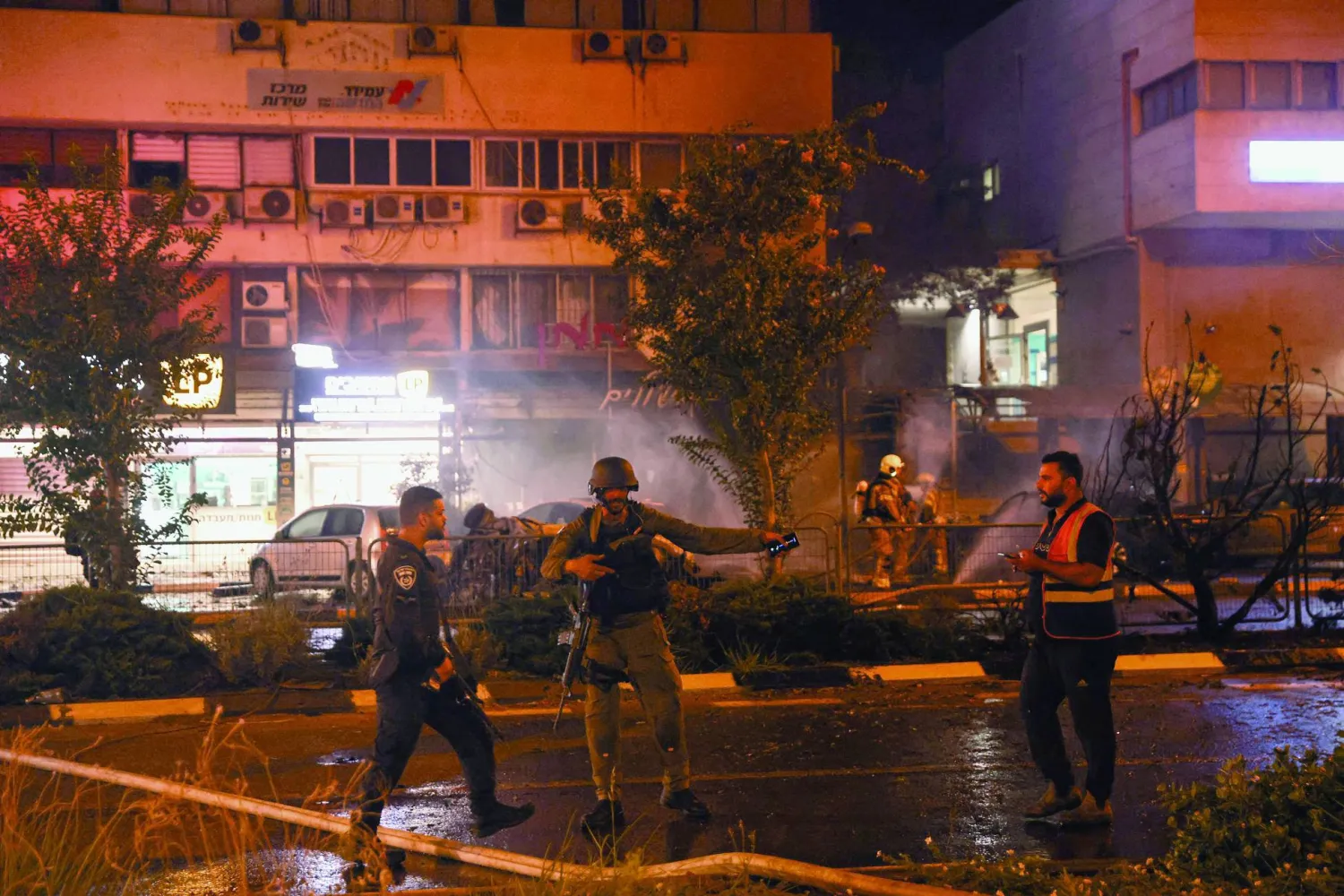 
جنود إسرائيليون يحيطون بالموقع الذي سقطت فيه القذائف التي أُطلقت من جنوب لبنان على كريات شمونة (أ.ف.ب)