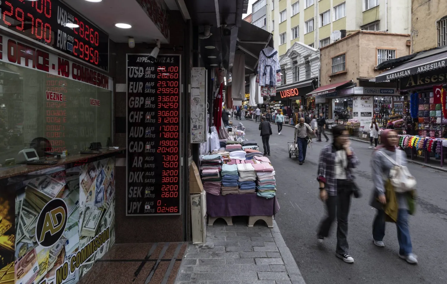 مشاة بجوار أحد محلات تصريف العملة في مدينة إسطنبول التركية (إ.ب.أ)