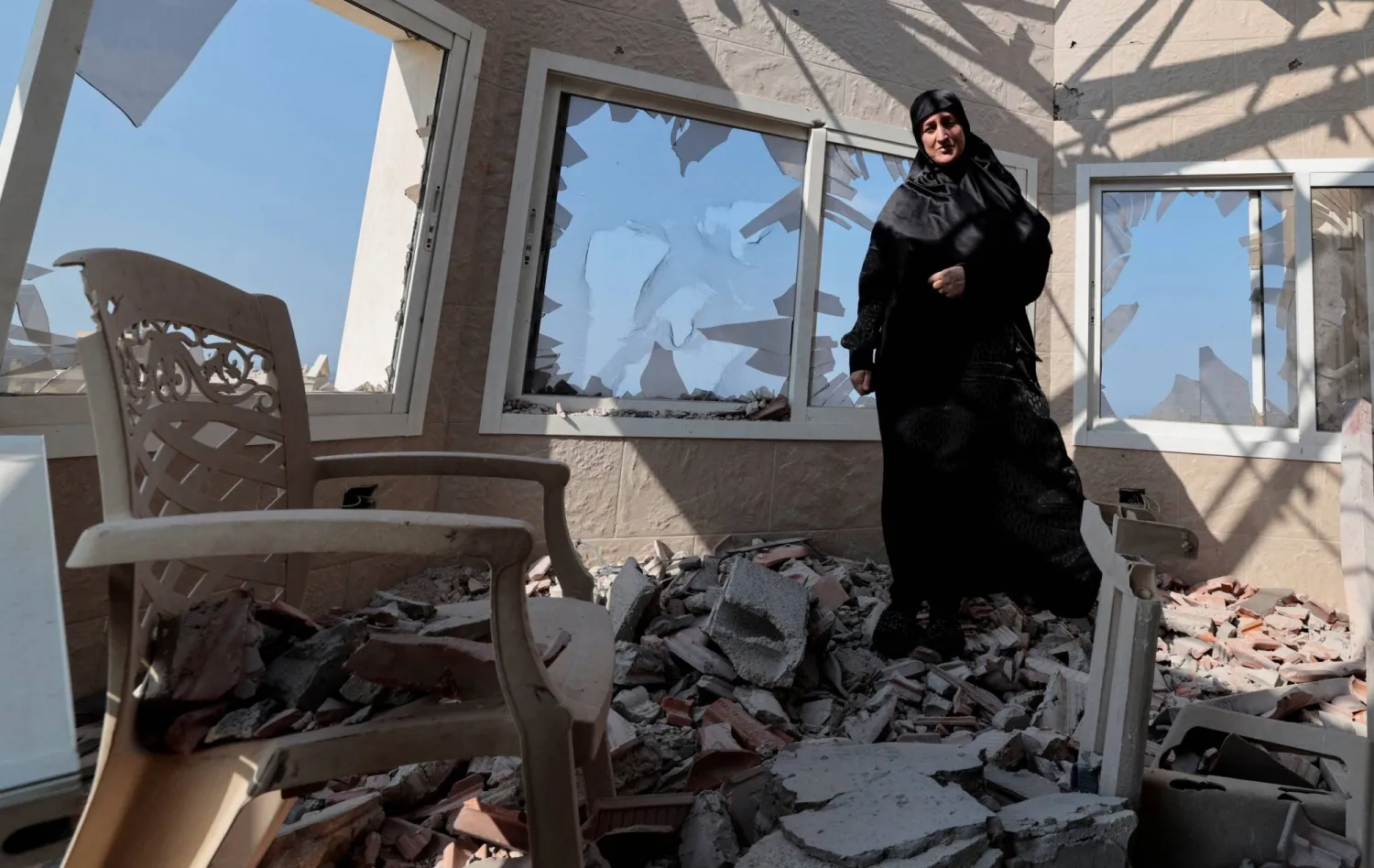 سيدة لبنانية داخل منزلها في بلدة ياطر الحدودية الذي تضرر بعد إصابته بقذيفة إسرائيلية (رويترز)