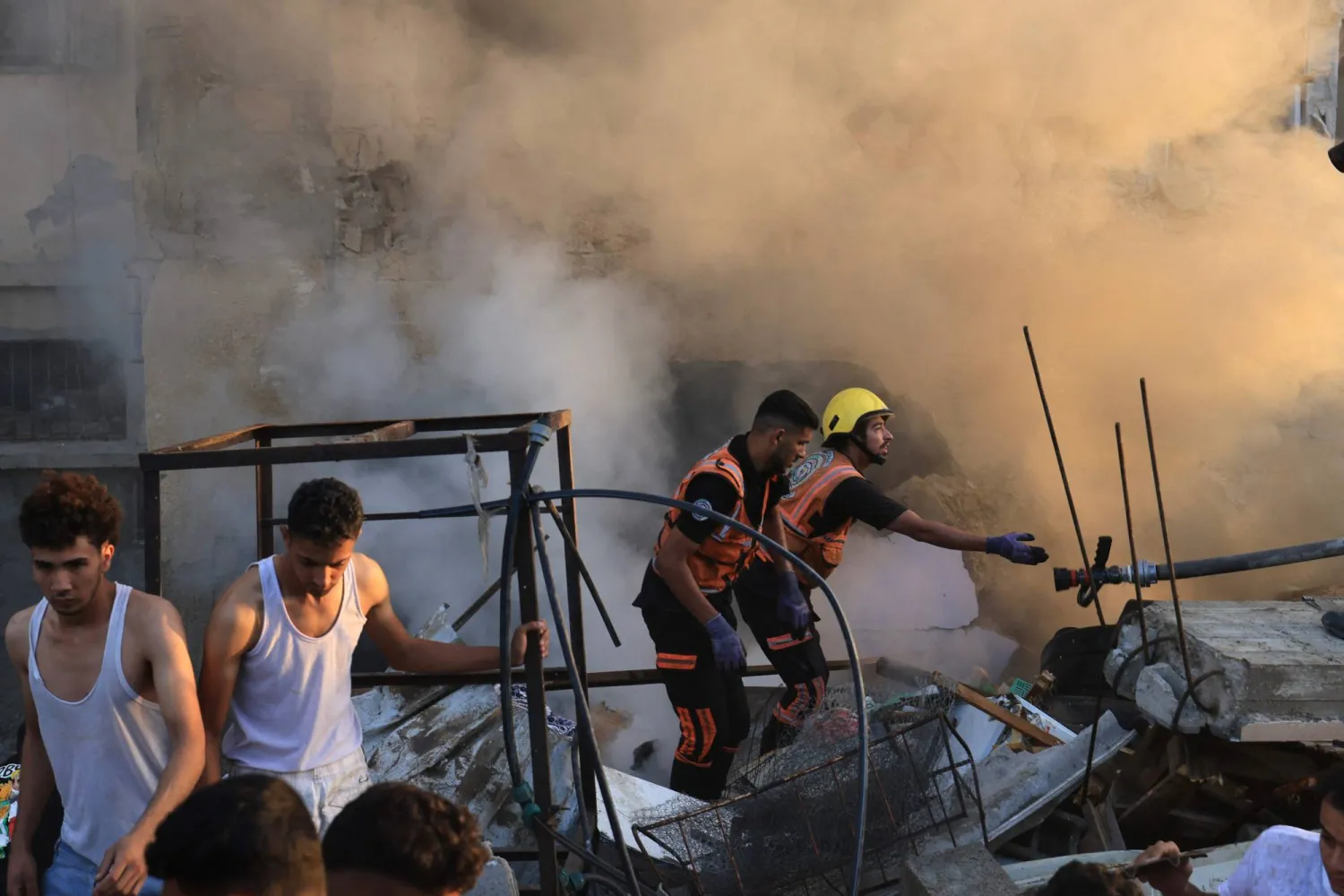 يتصاعد الدخان بينما يقف رجال الإنقاذ الفلسطينيون على أنقاض مبنى منهار في أعقاب غارة شنها الجيش الإسرائيلي على خان يونس (أ.ف.ب)