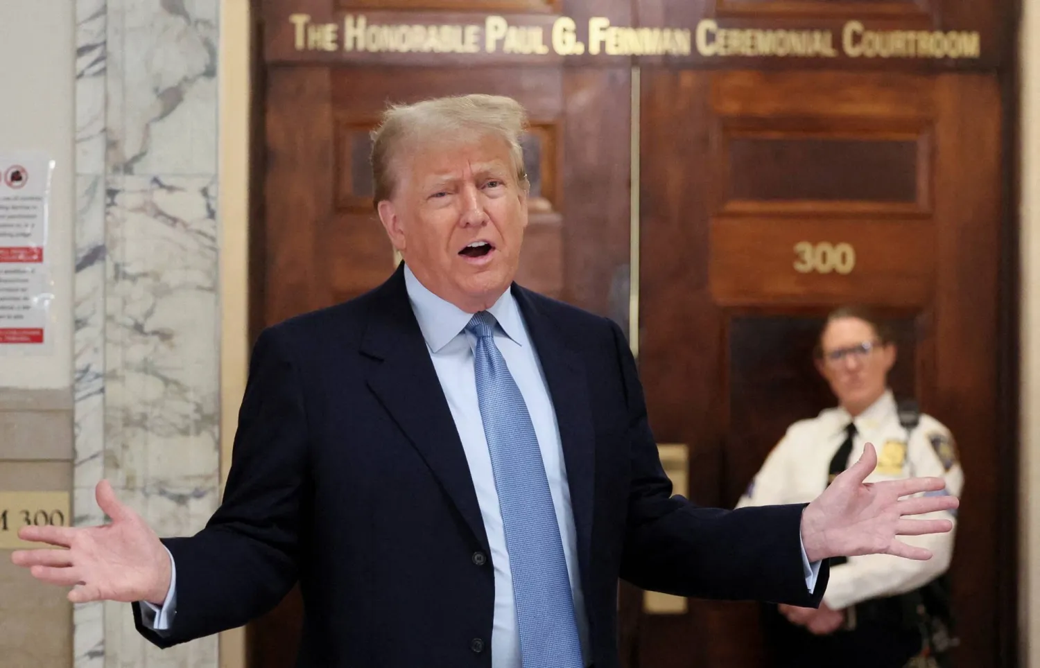 دونالد ترمب تحدث في الردهة أثناء حضوره محاكمته في محكمة مانهاتن في قضية احتيال مدني في نيويورك الشهر الماضي (رويترز)