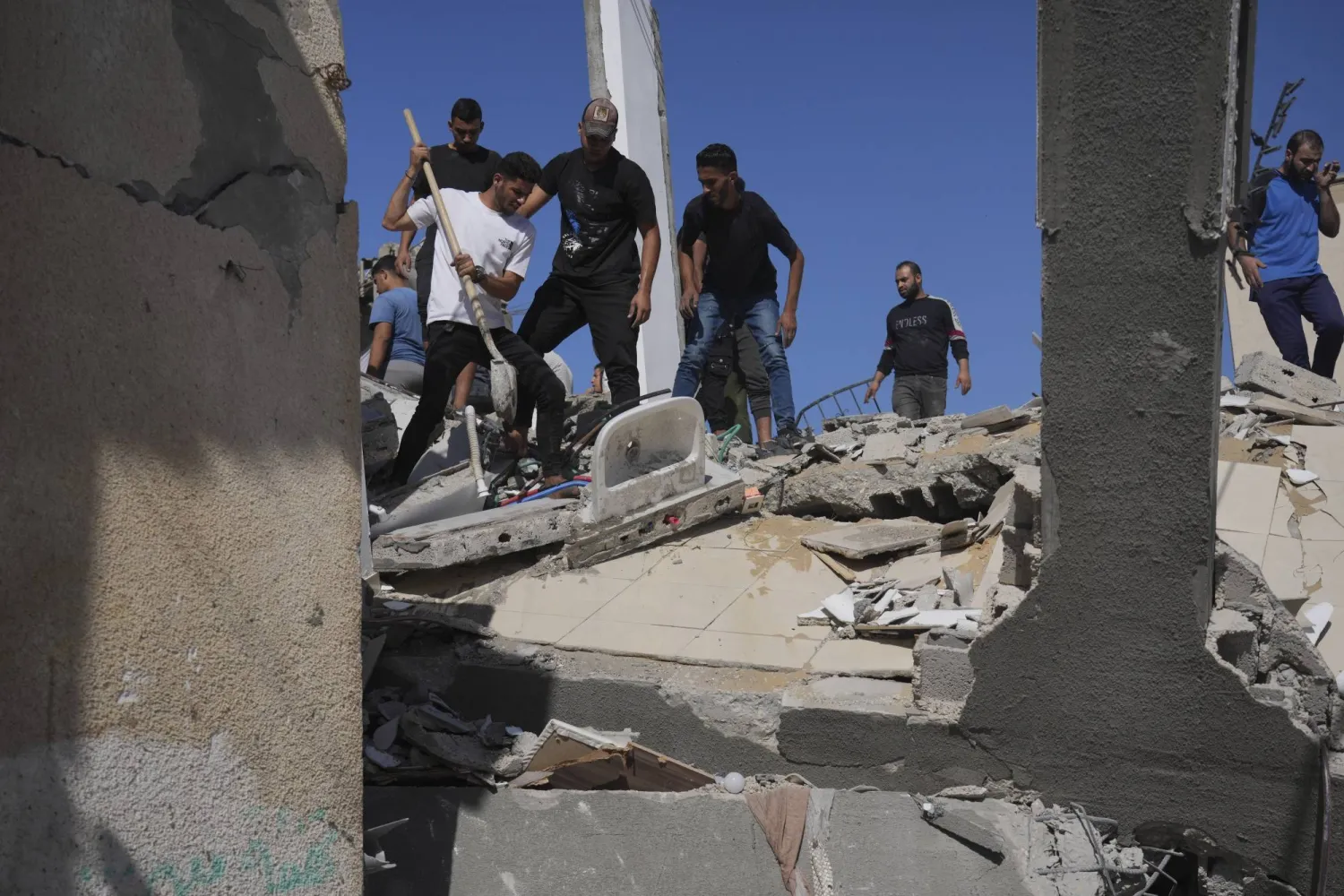 فلسطينيون يبحثون عن ناجين من القصف الإسرائيلي في مشرحة دير البلح (أ.ب)