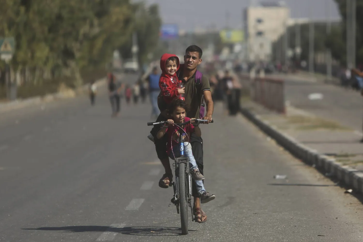 فلسطيني يهرب وطفله من الحرب في غزة على دراجة (أ.ب)