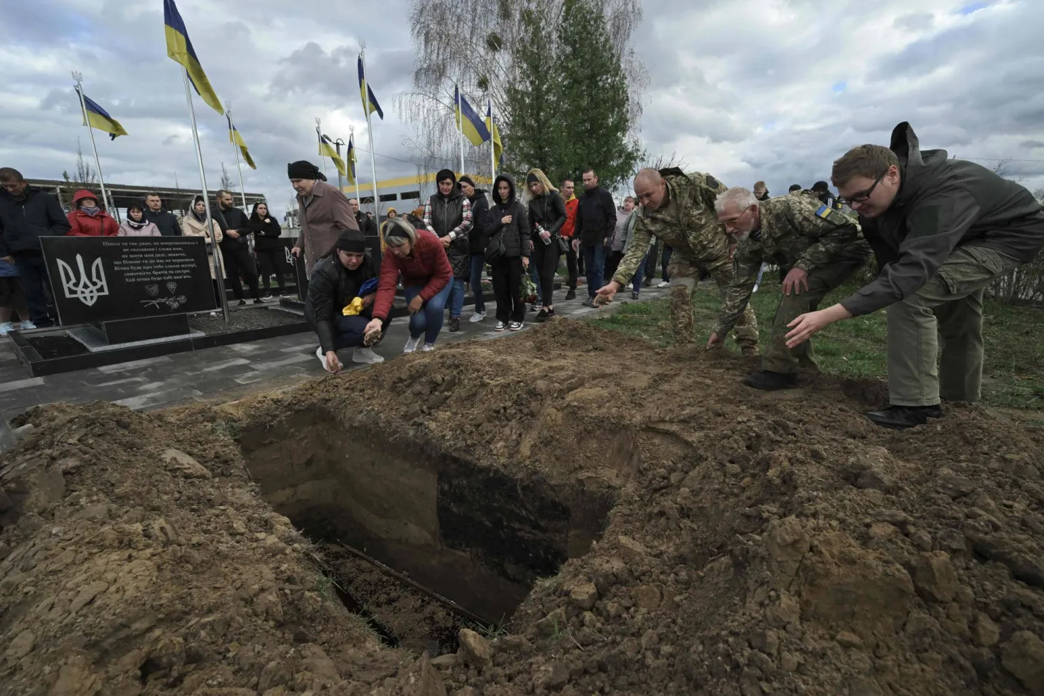 أقارب وأصدقاء يرشقون التراب أمام نعش الجندي الأوكراني الراحل فيتالي كامينسكي (33 عاماً)، خلال مراسم جنازة في مقبرة في بوتشا، خارج كييف في 6 نوفمبر 2023، وسط الغزو الروسي لأوكرانيا (أ.ف.ب)