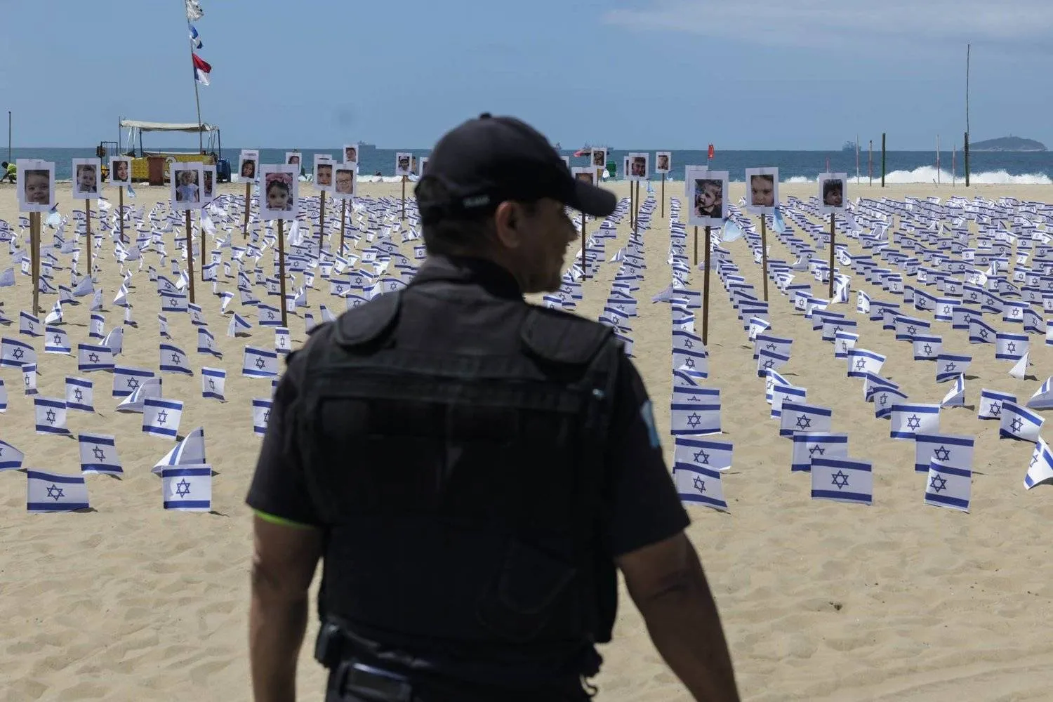 A military policeman observes Israeli flags and photographs placed on Copacabana Beach by the NGO Rio de Paz, symbolizing the victims of the Hamas attack on October 07, in Rio de Janeiro, Brazil, 07 November 2023. EPA/Antonio Lacerda