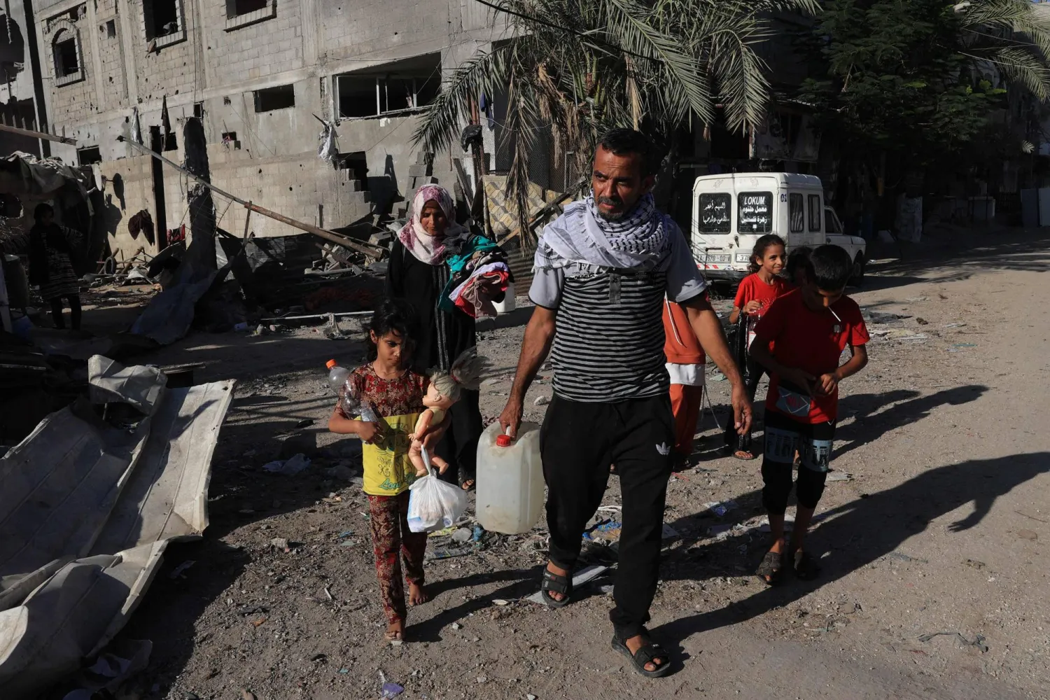 أمل الربايعة وزوجها عماد وأطفالهما يسيرون من منزلهم الذي دمره هجوم إسرائيلي باتجاه مدرسة تابعة للأمم المتحدة (أ.ف.ب)