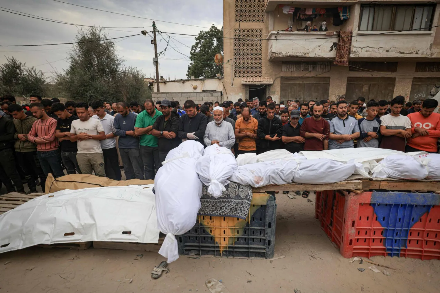 فلسطينيون يصلّون صلاة الجنازة قبل تشييع أفراد عائلتيْ قديح والشرفي الذين قُتلوا في غارات ليلية على جنوب قطاع غزة، في خان يونس (أ.ف.ب)
