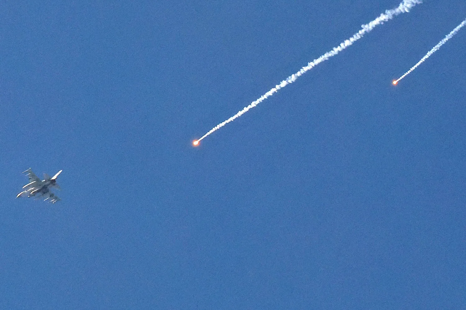 طائرة تابعة للقوات الجوية الإسرائيلية تطلق قنابل مضيئة أثناء تحليقها فوق موقع على طول الحدود مع قطاع غزة (أ.ف.ب)