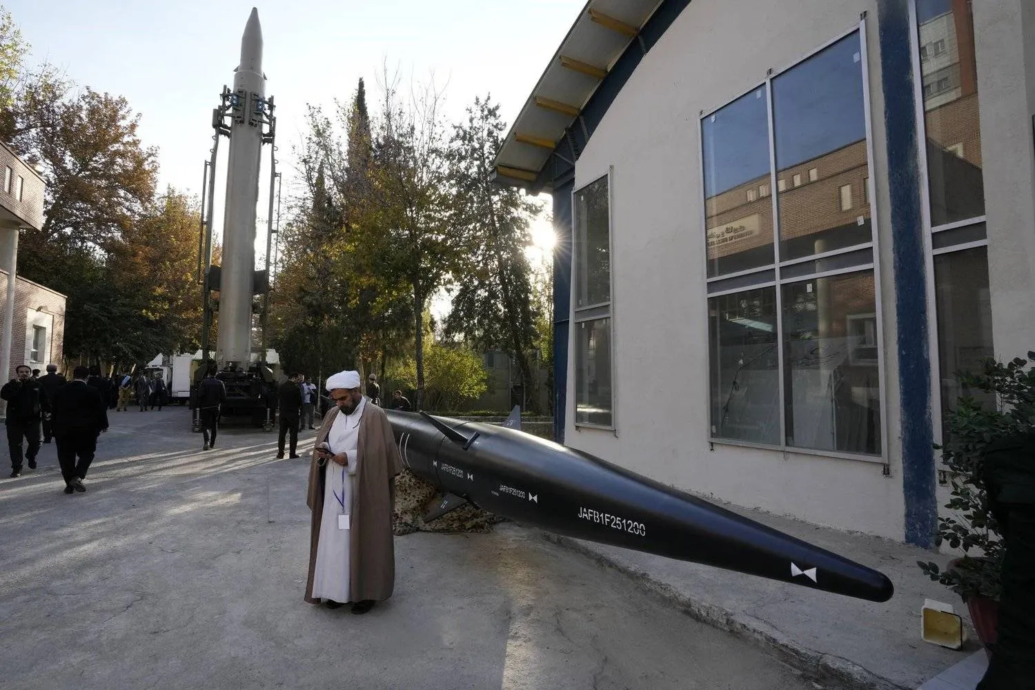 An Iranian cleric uses a mobile phone while standing beside missiles on display in Tehran on Monday. (AP) 