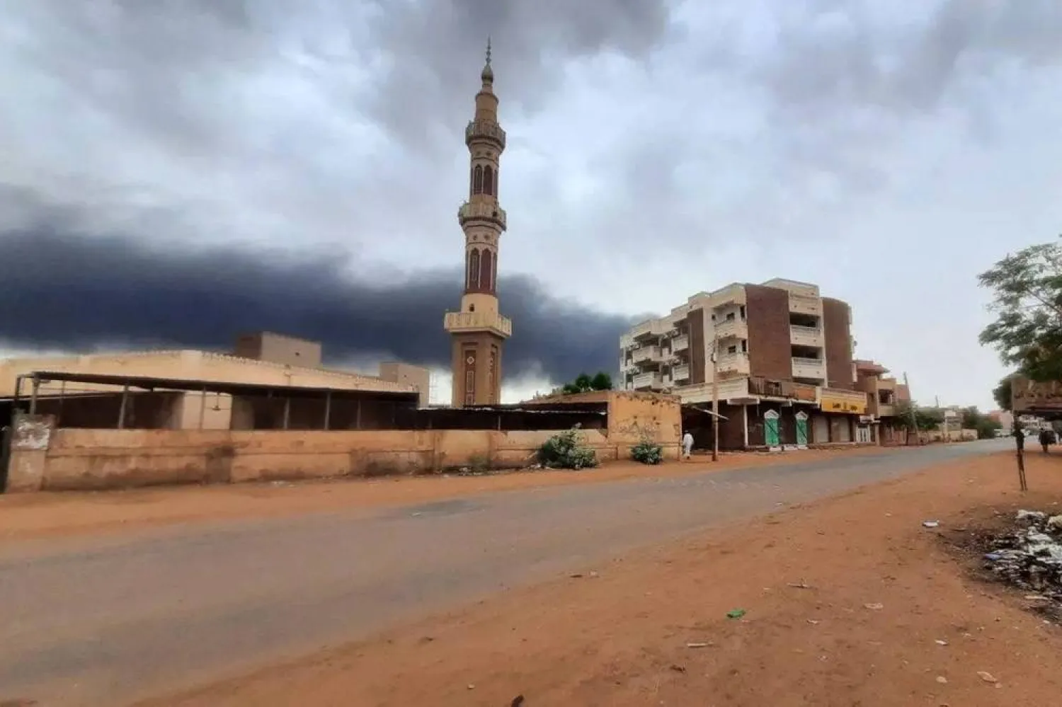 Smoke rises above buildings behind a nearly deserted street in Khartoum, on June 10, 2023. (AFP via Getty Images)