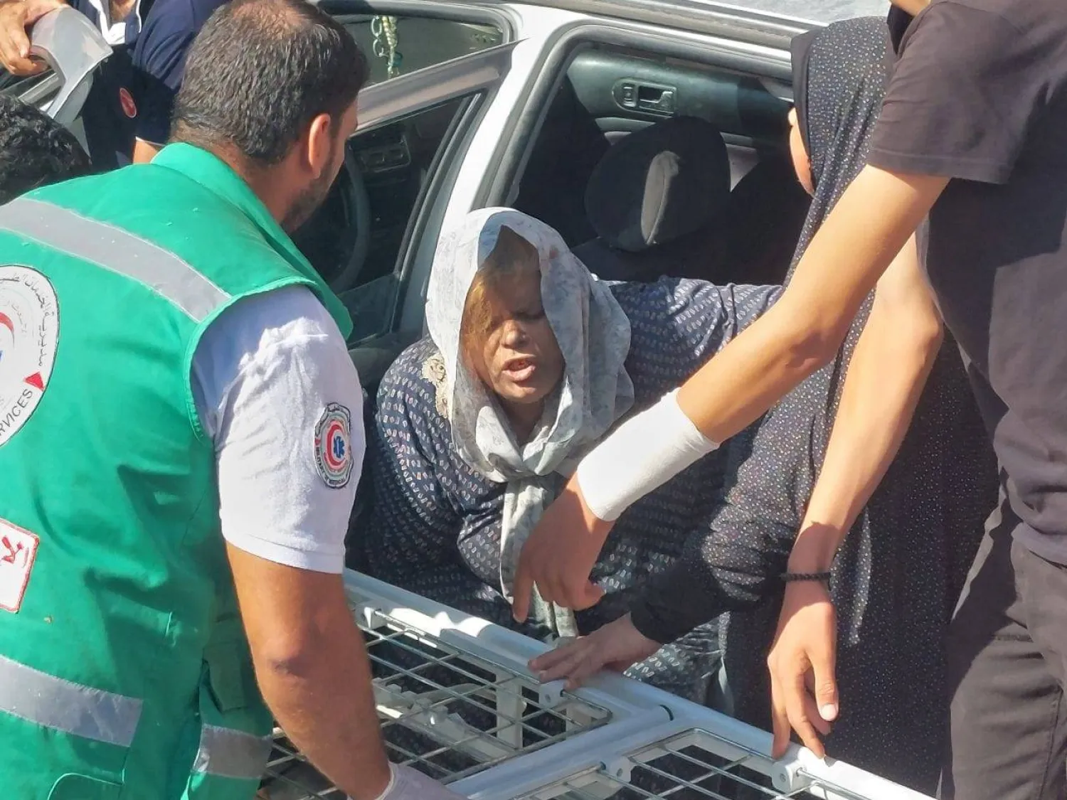 سيدة فلسطينية تصل إلى عربة ويساعدها أحد أفراد الهلال الأحمر في قطاع غزة (وكالة أنباء العالم العربي)