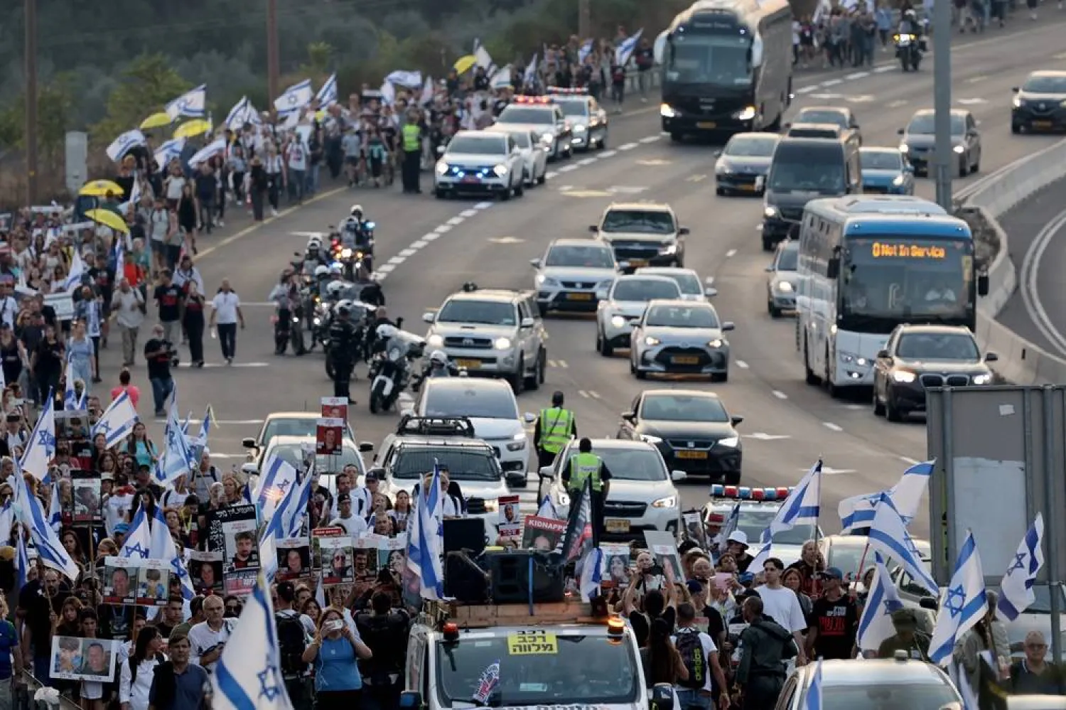 Relatives, friends and supporters of Israeli hostages held in the Gaza Strip since the October 7 attack by Hamas militants in southern Israel, hold the Israeli flag, placards and images of those taken during a protest calling for their release as they march towards Jerusalem on November 17, 2023, amid the ongoing battles between Israel and the Palestinian group Hamas. (AFP)