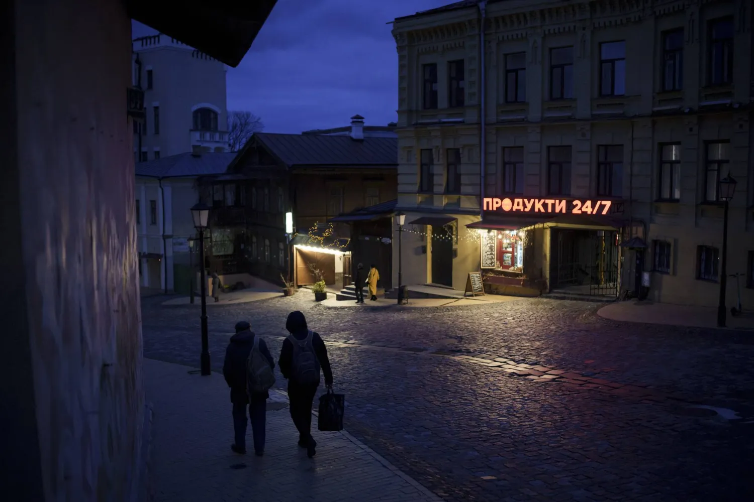 People walk at dusk in central Kyiv, Ukraine, Saturday, Nov. 18, 2023. (AP Photo/Felipe Dana)