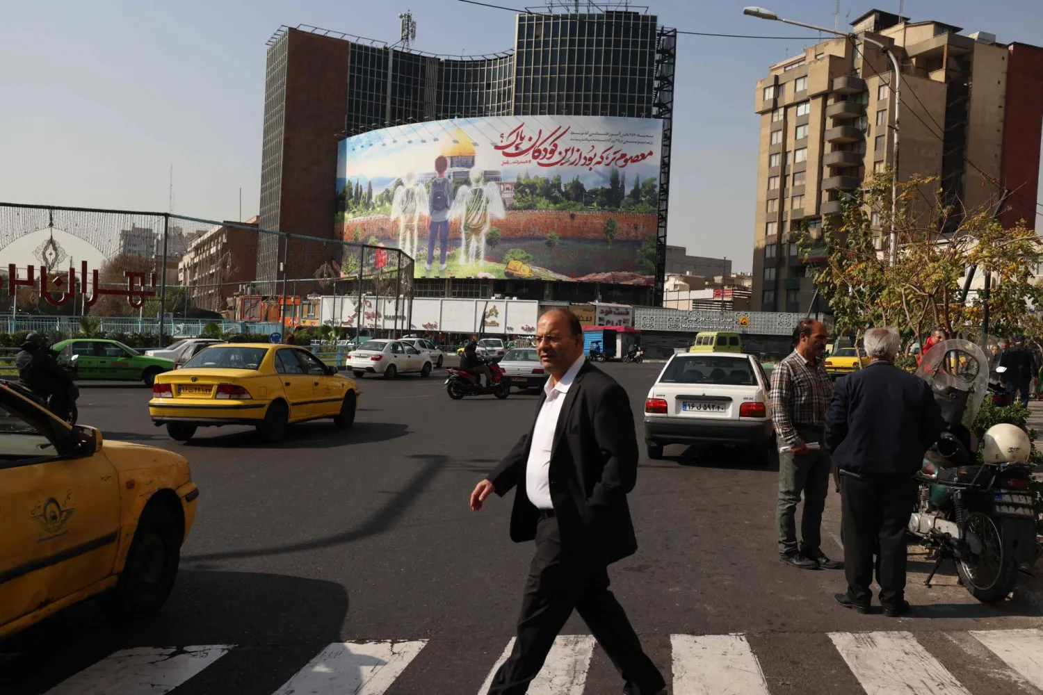 أشخاص يمرون أمام لوحة إعلانات كبيرة تدين قتل الأطفال في غزة، في طهران 11 نوفمبر الحالي (أ.ف.ب)