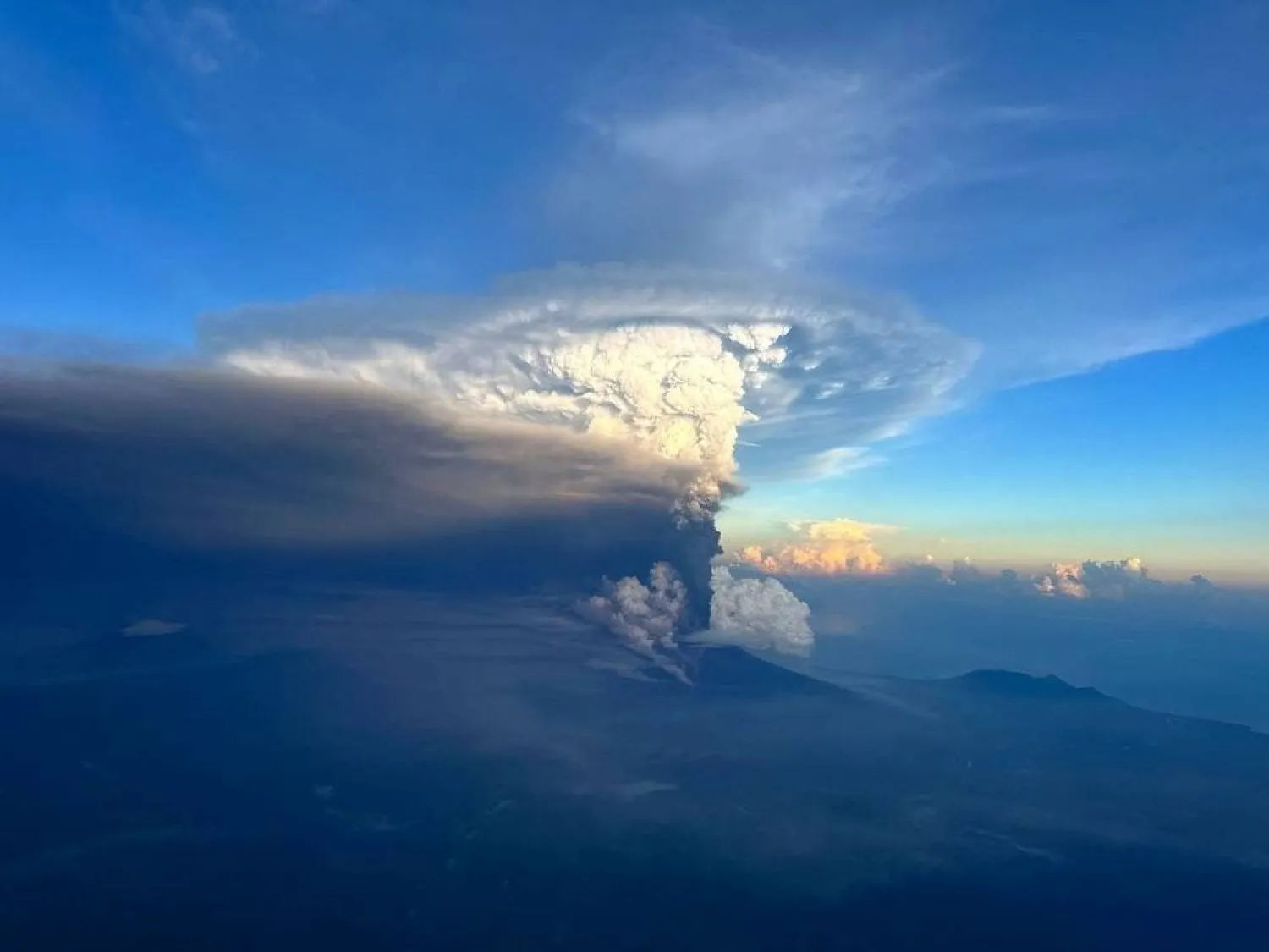 Ash column rises from Mount Ulawun, as seen from an airplane window, Papua New Guinea November 21, 2023, in this picture obtained from social media. (Enoch Lapa/via Reuters) 