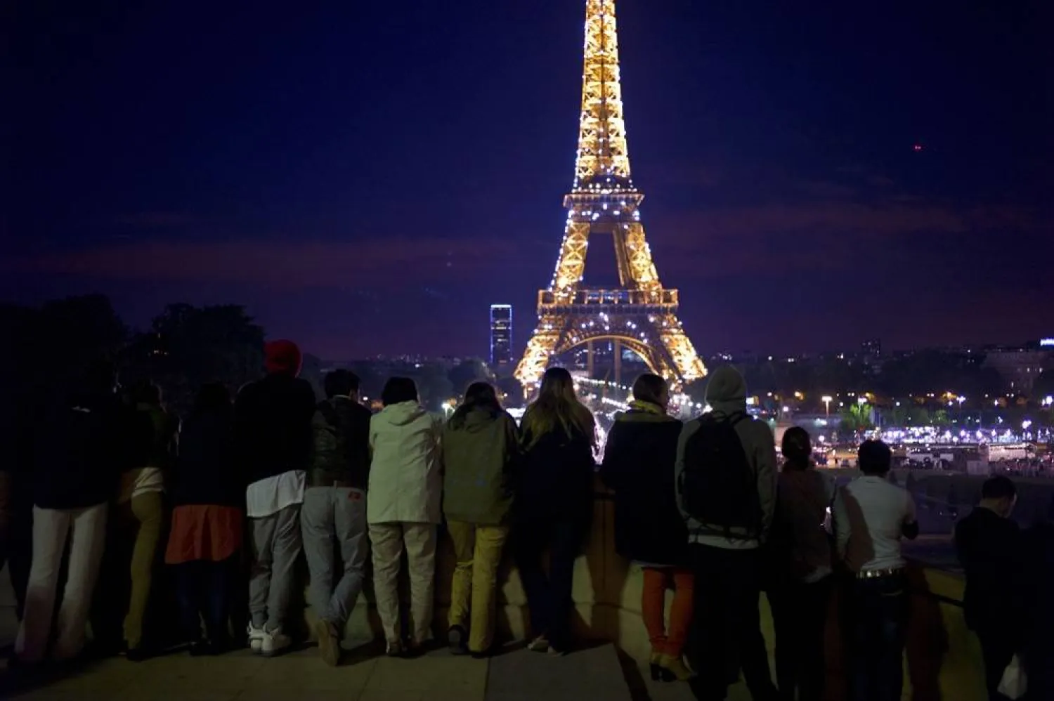 Tourists look at the illuminated Eiffel Tower in Paris, on June 13, 2013. (AP)