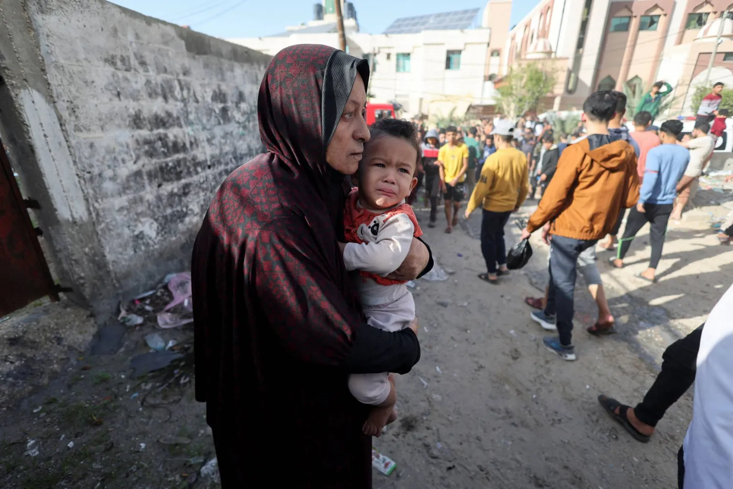 سيدة فلسطينية تحمل طفلاً بعد غارة إسرائيلية على منزل في رفح بجنوب قطاع غزة أمس (رويترز)
