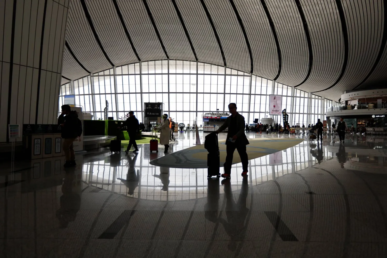 Travellers walk with their suitcases at Beijing Daxing International Airport in Beijing, China April 24, 2023. REUTERS/Tingshu Wang/File photo