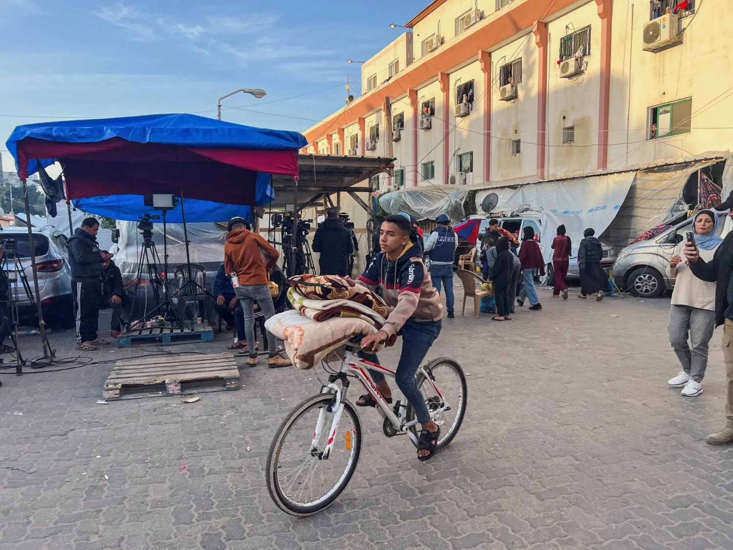 فلسطيني نازح فر من منزله بسبب الغارات الإسرائيلية، يركب دراجته مع متعلقاته أثناء مغادرته «مستشفى ناصر» في خان يونس بجنوب قطاع غزة (رويترز)